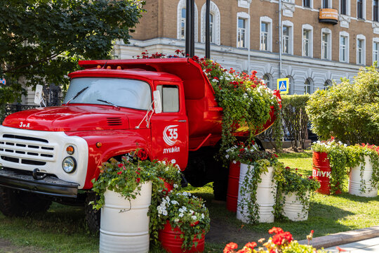 Moscow, Russia - July 18, 2026: Front view of a vintage red truck with Lukoil brand logo surrounded by flower planters