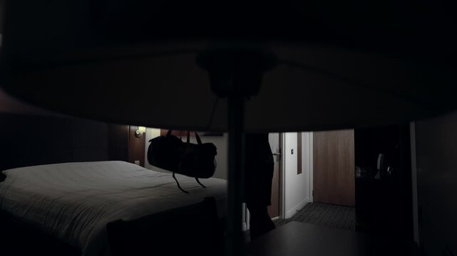 A man entering a dark hotel room with his bag