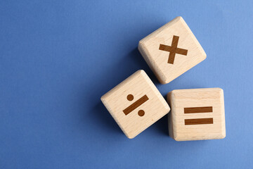 Obraz na płótnie Canvas Wooden cubes with mathematical symbols on blue background, top view. Space for text