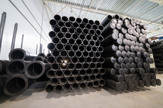 Storage area with large quantities of black pipes arranged in stacks ready for use