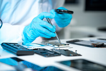 Technician in blue gloves repairs an opened smartphone with precision tools at a clean electronics...