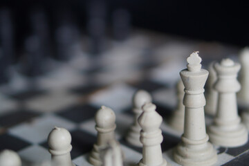 Close up, A chessboard with white pieces against a black background, a game that relies on strategy and intellectual acuity. © Randa