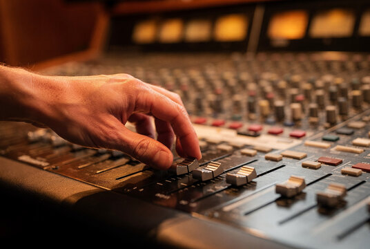 Hand Adjusting Faders on a Professional Audio Mixing Console