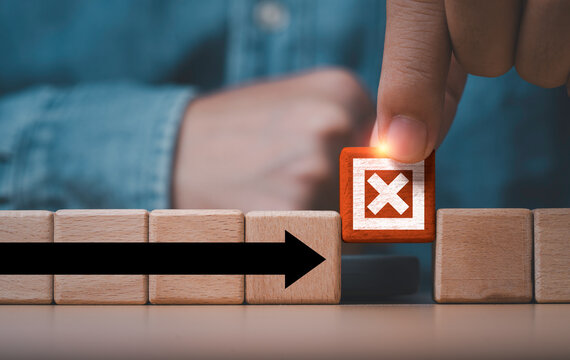 Business risk management and problem solving concept with a hand removing a wooden block marked X from an arrow path symbolizing obstacle removal, strategic decisions and business continuity.