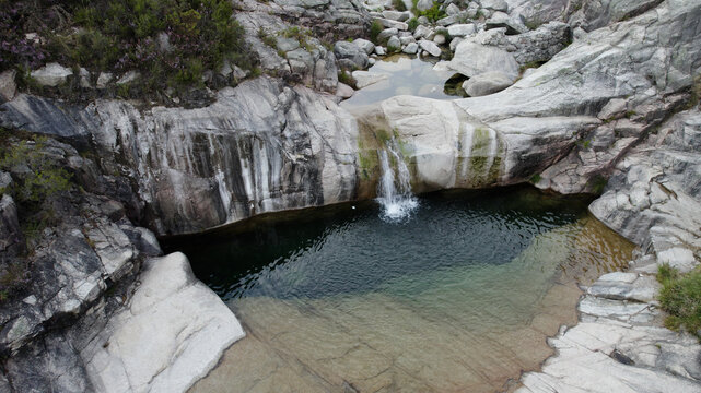 Aerial view of the Pocos Verdes, a natural rock pool with clear water and a small waterfall, surrounded by granite rock formations in Cabril, Vila Real, Portugal.