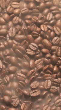 Freshly roasted coffee beans in motion &ndash; close-up (macro) - shrouded in rising smoke and steam. Vertical view.