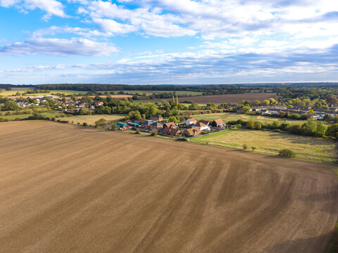 Idyllic drone view of wide-open farmland in rural Essex, UK. Around mid-centre is a small, new housing development at the edge of the village of Blackmore.