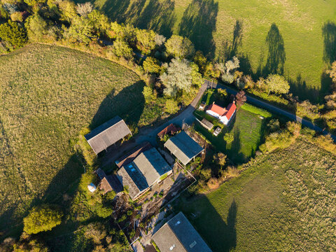 Dusk view of a small, derelict dairy farm in Essex, UK as seen from a drone&rsquo;s perspective. Many of the outbuildings are in disrepair. The white-walled farmhouse is on on the upper part if the image.