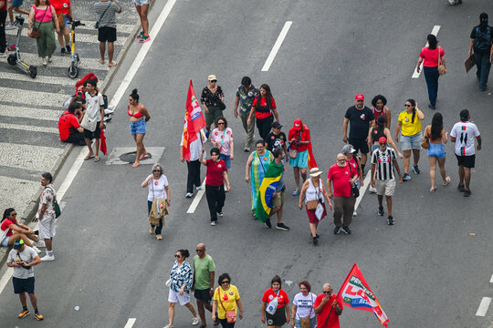Rio de Janeiro, Rio de Janeiro, Brazil - 12 October 2026: Aerial view of a political demonstration with supporters walking along the street, carrying flags and wearing red clothing.