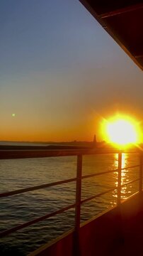 Cinematic real-time video of a beautiful golden sunset over the Bosphorus Strait in Istanbul, shot from a moving ferry boat.