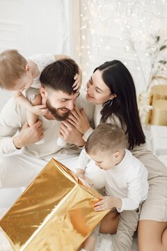 Young family in white clothes opening Christmas gifts at home