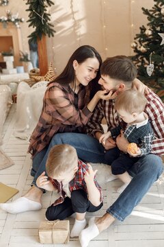 Young family in plaid shirts sitting near Christmas tree