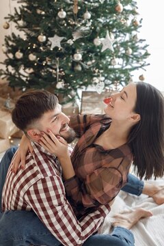 Romantic couple sitting near Christmas tree and hugging