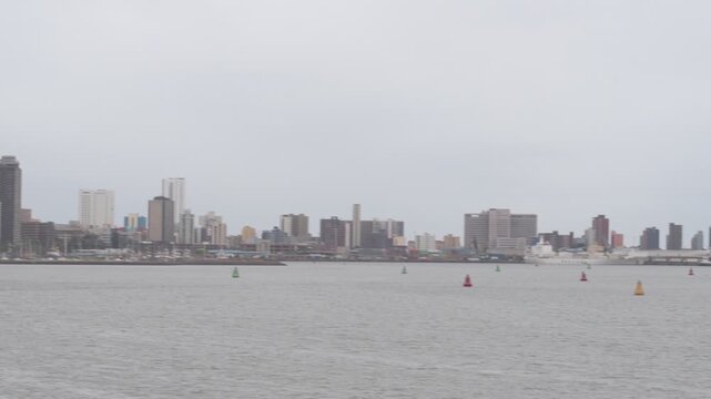 panoramic perspective across the port of durban harbor with cargo vessels moored at terminal berths, port warehouses, industrial settlements and the coastal city skyline