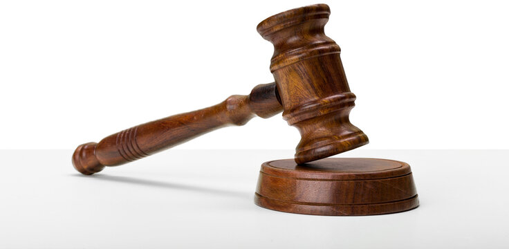 Wooden gavel rests on a round base on a white surface indicating legal proceedings