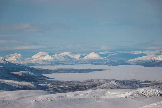 Snow-covered mountains and frozen lakes across Abisko National Park in Swedish Lapland, Sweden