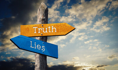 Truth and lies - wooden signpost with two arrows, sunset sky in background © PX Media