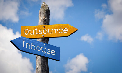 Outsource or inhouse - wooden signpost with two arrows, sky with clouds © PX Media