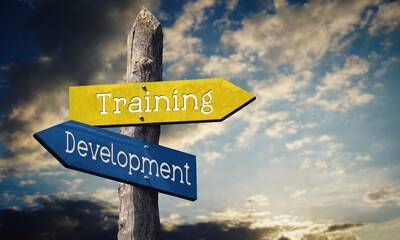 Training and development - wooden signpost with two arrows, sunset sky in background © PX Media