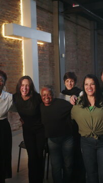 Diverse group of happy church members sharing a warm group hug after Sunday worship service to foster community togetherness and love