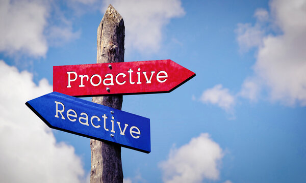 Proactive or reactive - wooden signpost with two arrows, sky with clouds