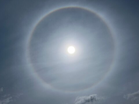 22 degree solar halo with bright sun in the center, circular ring in blue sky