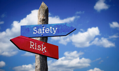 Safety and risk - wooden signpost with two arrows, sky with clouds © PX Media