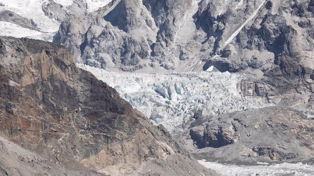 Majestic view of massive glacier surrounded by rocky mountain peaks, revealing stark and raw power of nature in rugged Himalayan environment under clear sky. Melting of ice glaciers in Nepal