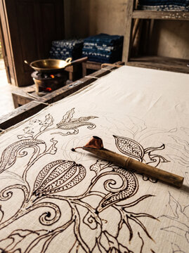 Hand-drawn batik tulis with copper canting and hot wax on undyed cotton in a traditional Indonesian workshop