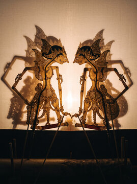 Traditional Javanese wayang kulit leather shadow puppets with hand-punched details backlit on a translucent screen