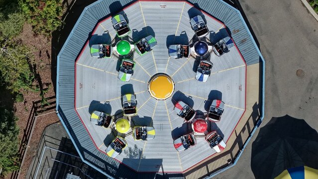 Aerial view of a colorful spinning amusement park ride with multiple cars on a circular platform in Denver, Colorado, United States.
