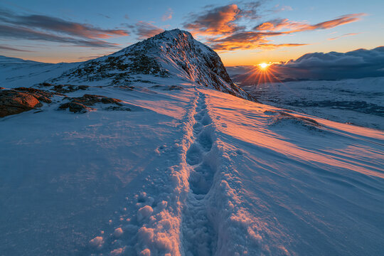 Snowy mountain trail with sunset view in a winter landscape