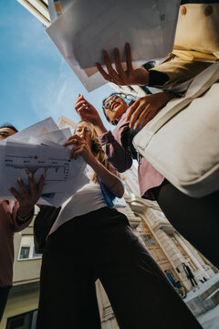 Woman and team review financial documents and charts during an outdoor meeting, supporting collaboration and strategy.