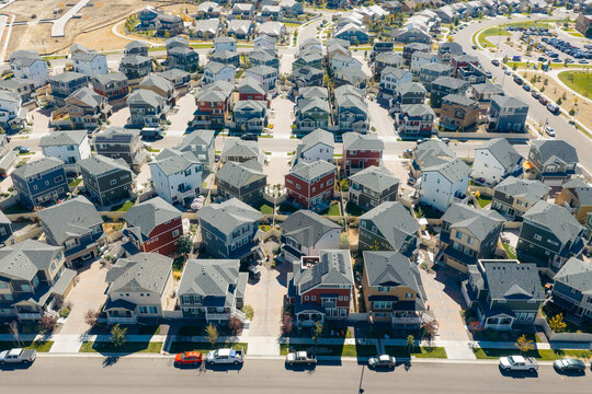 Aerial view of a modern suburban residential development featuring rows of single-family homes with diverse roof colors, paved streets, and landscaped yards in Erie, Colorado, United States.