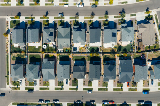 Aerial view of modern suburban residential development with rows of single-family homes, neatly arranged streets, green lawns, and parked cars in a planned community Erie, Colorado, United States.