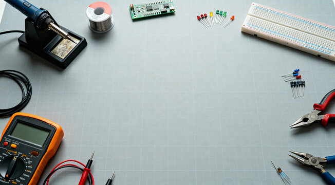 Electronics workbench background with soldering iron, multimeter, breadboard and electronic components for diy projects and testing