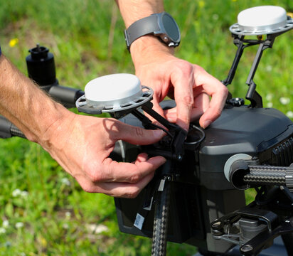 Close-up of engineer's hands setting up GNSS RTK antennas on a professional industrial drone outdoors