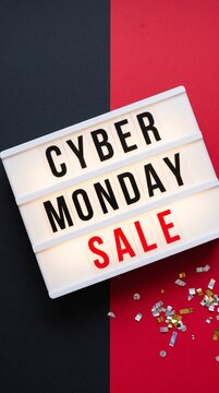 Cyber Monday sale sign with bright illumination, set against a split background of black and red, with scattered confetti