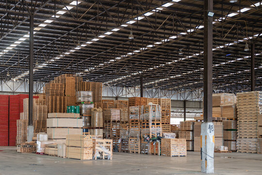 Stacked lumber occupies a timber warehouse where wooden pallets and crates stand beside large stacks of sawn boards.