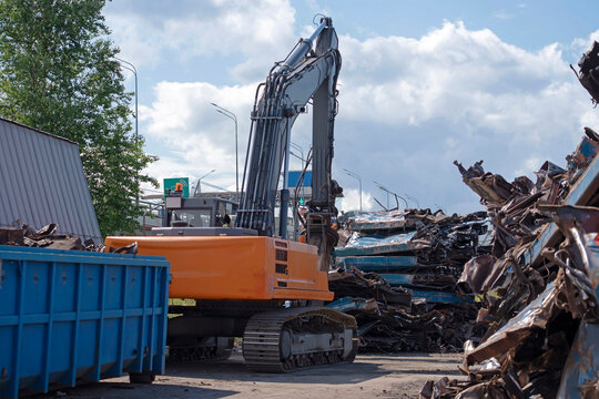 Heavy excavator works among discarded railway carriages and metal debris at an industrial rail scrapyard, illustrating vehicle dismantling and scrap recovery.