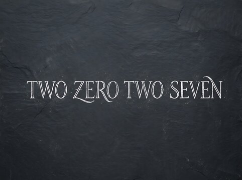 Elegant lettering of the year two zero two seven written on a textured dark stone background