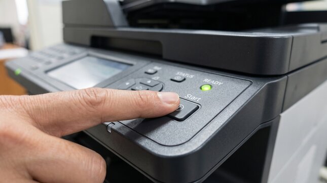 Finger pressing start button on multifunction printer panel with green ready indicator