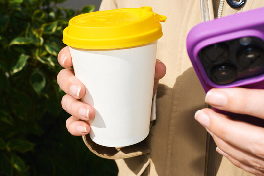 Person with coffee and phone outside