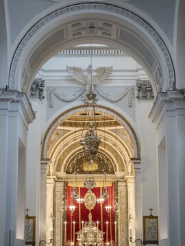 Looking through white marble arches at the ornate silver altar and red velvet drapery inside the historic Palermo Cathedral in Sicily.