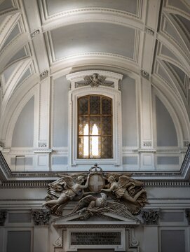 Vertical shot of interior wall detail inside Palermo Cathedral showing Neoclassical relief of angels holding  crowned shield above a window and vaulting.