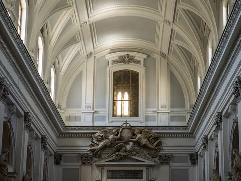 Artistic vertical composition detailing the structural plasterwork, vaulted ceiling arches, leaded window, and angel relief sculpture inside Palermo Cathedral.