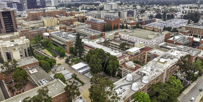 Aerial view of the UCLA campus featuring historic brick buildings, lush green trees, and pedestrian walkways in Westwood, California, United States.