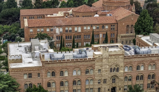 Aerial view of the historic red brick buildings of the UCLA Campus featuring intricate architectural details and surrounding lush green trees, Westwood, California, United States.