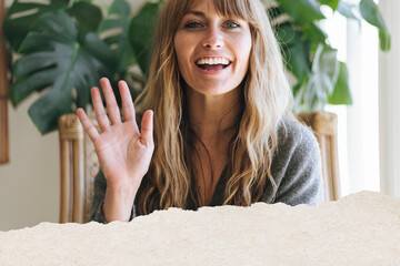 Smiling woman waving in cozy home setting © Rawpixel.com
