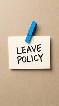 Paper note with LEAVE POLICY text pinned by blue clothespin on beige background, employee time off, vacation rules, HR guidelines, workplace regulations, company policy concept